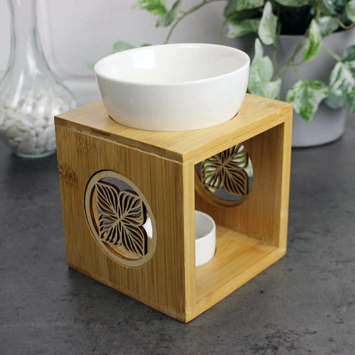 Bamboo diffuser with a white bowl on top, placed on a dark surface with a blurred background.
